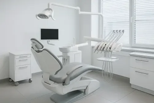 A dental chair, overhead light and instrument tray in a bright white operatory