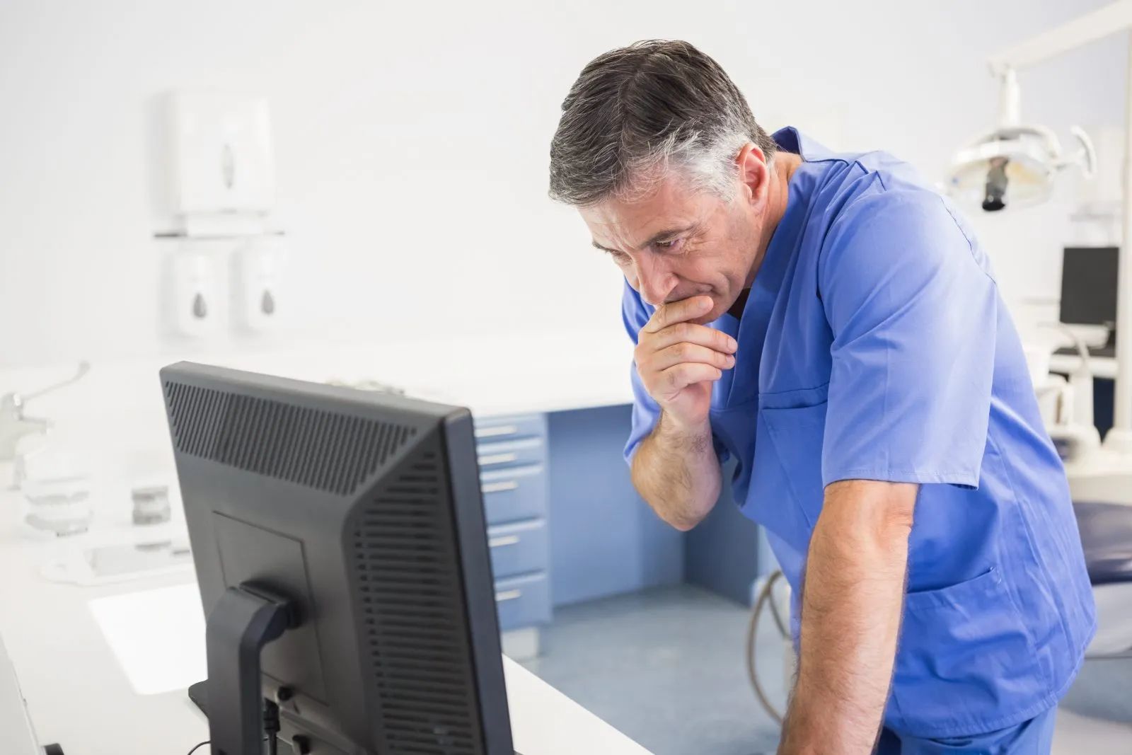 A dental practice owner reviewing figures at a screen